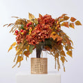 Golden Hour Fall Hydrangea, Birch Leaf, Orange Crater Berry & Yellow Astilbe Water Illusion Arrangement in Rattan Vase